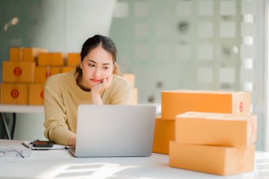Small business startups, SME owners, Asian women entrepreneurs Successfully working with boxes and checking online orders with a laptop to prepare. Sell to customers. Online SME Business Ideas