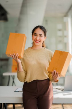 Small business startups, SME owners, Asian women entrepreneurs Successfully working with boxes and checking online orders with a laptop to prepare. Sell to customers. Online SME Business Ideas