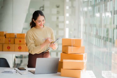 Small business startups, SME owners, Asian women entrepreneurs Successfully working with boxes and checking online orders with a laptop to prepare. Sell to customers. Online SME Business Ideas
