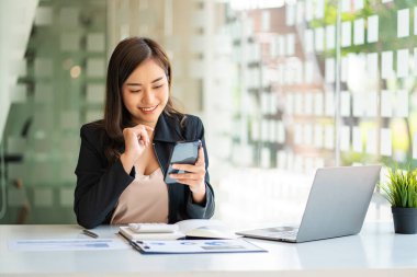 Asian business woman working in finance with laptop and smartphone, accounting concept.