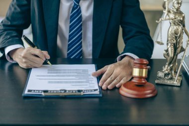 A judge's hammer and scales of justice and a jurisprudence book on a table in a lawyer's office. Provide legal advice to clients regarding business law. Law in everyday life.