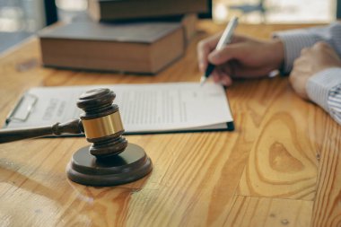 A judge's hammer and scales of justice and a jurisprudence book on a table in a lawyer's office. Provide legal advice to clients regarding business law. Law in everyday life.
