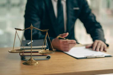 A judge's hammer and scales of justice and a jurisprudence book on a table in a lawyer's office. Provide legal advice to clients regarding business law. Law in everyday life.