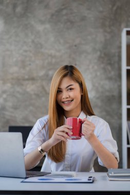 Attractive Asian female accountant for budgeting. Company expenses and income from the report plan for spending money work on the desk at home financial accounting calculator