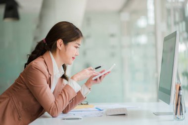 Beautiful Asian female accountant working on finance with business report and financial calculator concept.