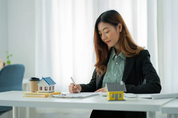 Portrait of a lovely Asian woman sitting in an office and home model. For real estate, business, finance and insurance concepts.