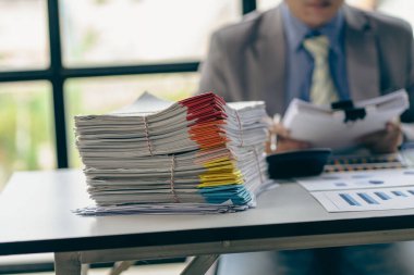Businessman working in financial accounting with piles of documents on the desk at home work from home concept, business report, pile of unfinished paperwork