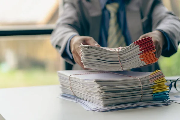 Businessman working in financial accounting with piles of documents on the desk at home work from home concept, business report, pile of unfinished paperwork