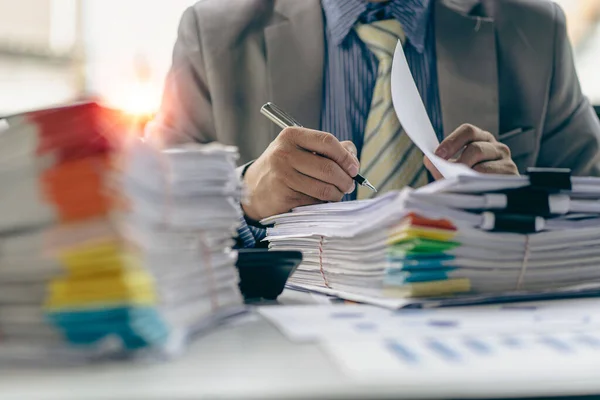 Businessman working in financial accounting with piles of documents on the desk at home work from home concept, business report, pile of unfinished paperwork