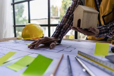 An engineer or architect working on a new project on a construction site. With blueprints and using a laptop draw a project design in the concept of an architectural engineer.