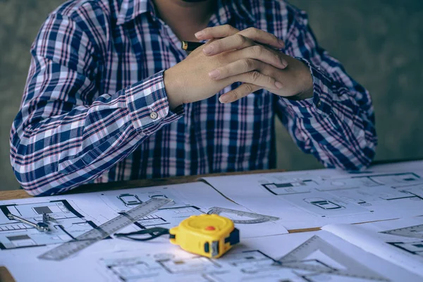 An engineer or architect working on a new project on a construction site. With blueprints and using a laptop draw a project design in the concept of an architectural engineer.