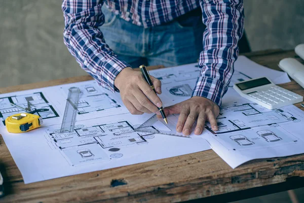 An engineer or architect working on a new project on a construction site. With blueprints and using a laptop draw a project design in the concept of an architectural engineer.