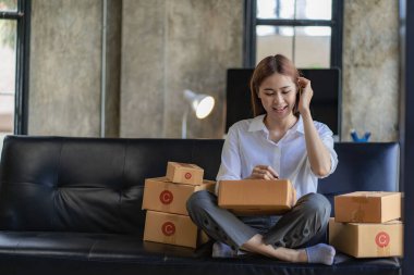 small entrepreneur Start an online selling business at home on the sofa by organizing items with yellow parcel boxes. SME business idea.