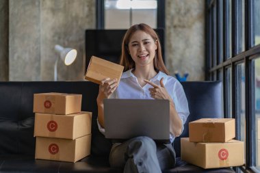 small entrepreneur Start an online selling business at home on the sofa by organizing items with yellow parcel boxes. SME business idea.
