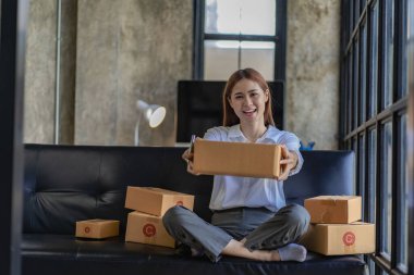 small entrepreneur Start an online selling business at home on the sofa by organizing items with yellow parcel boxes. SME business idea.