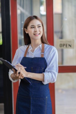 Asian woman standing at the door with a sign opening a food and drink concept.
