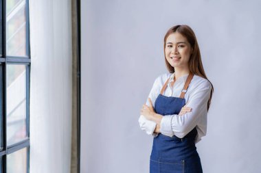 A young Asian waitress wears an apron. The caf owner stood at the door waiting for customers. small business idea