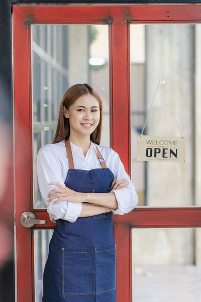 Asian woman standing at the door with a sign opening a food and drink concept.
