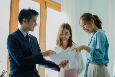 A group of cheerful modern Asian businessmen working together. Sit at a table discussing new project discovery solutions to increase effective communication ideas. chart on whiteboard