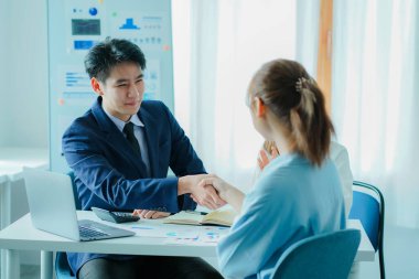 Smiling Caucasian businessman shaking hands greets female business partner with a successful meeting agreement. who are happy hand in hand, make a deal or get acquainted with an office briefing