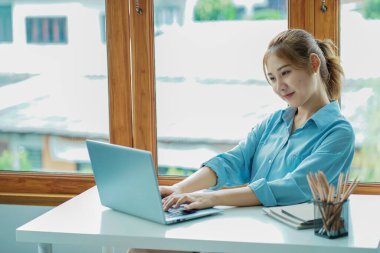 Attractive young Asian beauty accountant in office using laptop and financial documents on office desk.