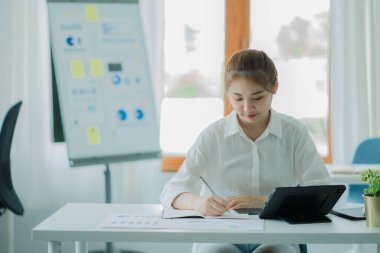Attractive young Asian beauty accountant in office using laptop and financial documents on office desk.