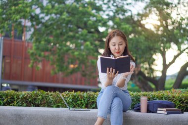 Young Asian college student with tiger skin and laptop sitting on the outdoor floor online learning concept outdoor