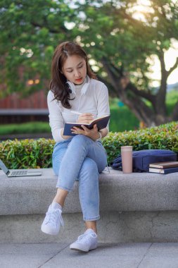 Young Asian college student with tiger skin and laptop sitting on the outdoor floor online learning concept outdoor