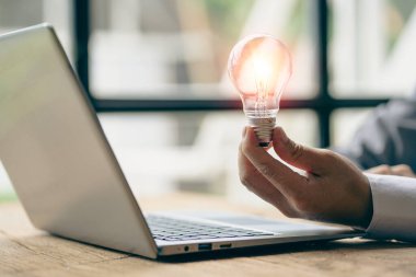 Innovation through inspiring ideas human hand holding a light bulb and creative Inspiration for sustainable business development, energy saving concept.