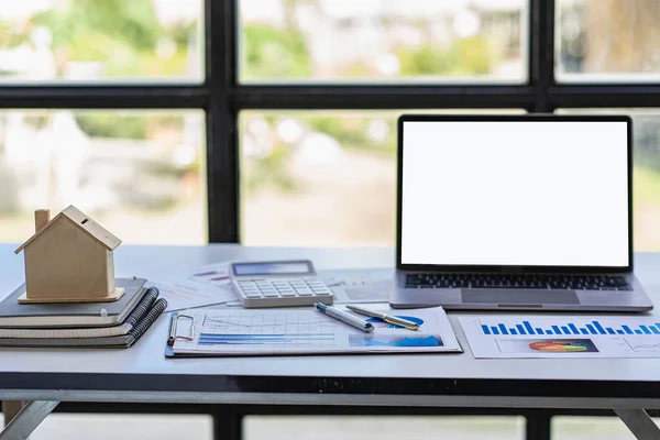 Real estate sales office with example of a house on a businessman\'s desk.