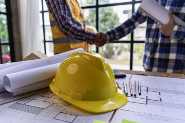 Engineers, architects, construction workers shake hands after project planning contract at desk in meeting room in office at construction site business concept contractor partnership construction