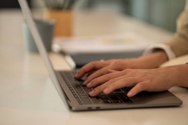 Close-up of a young woman working on a laptop surfing the web and browsing the Internet.