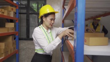 A female Asian warehouse worker checks inventory at the company's warehouse site. delivery concept