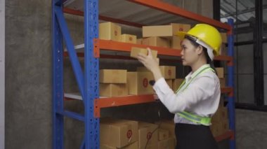 A female Asian warehouse worker checks inventory at the company's warehouse site. delivery concept
