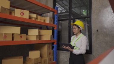 A female Asian warehouse worker checks inventory at the company's warehouse site. delivery concept