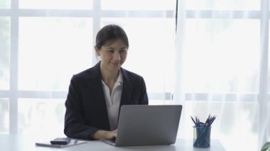 Attractive, smart, Asian woman using a laptop computer. work online from home at the living room