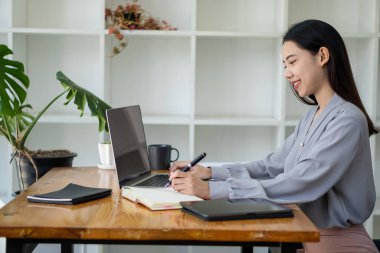 Asian woman working in office with laptop and tablet online working concept