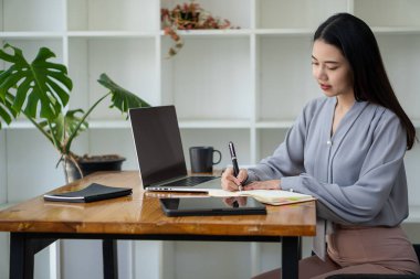 Asian woman working in office with laptop and tablet online working concept