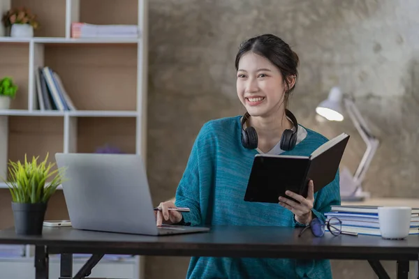 Smiling Asian woman using headset looking at laptop screen listen and learn online courses with a video call with headphones for online learning