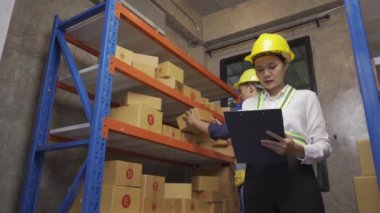 Two male and female employees inspecting the goods in the warehouse for delivery.
