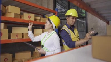 Two male and female employees inspecting the goods in the warehouse for delivery.