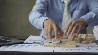 Businessman builds stairs from wooden blocks on the company's strategic plan development office desk. Help find new effective solution ideas for success.