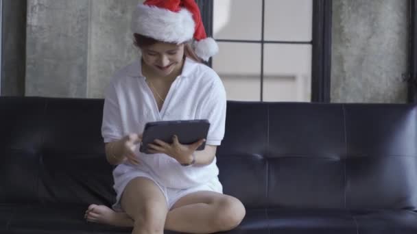 Asian Woman White Shirt Wearing Red Santa Hat Playing Tablet — Stockvideo