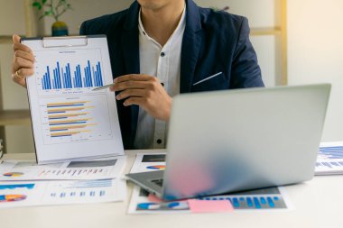 Yakın plan iş konsepti, muhasebeci holding grafik belgesi mali veri raporunu hesaplamak için hesap makinesi üzerinde çalışıyor. Ofisteki muhasebe belgeleri ve dizüstü bilgisayarı, yakın plan.