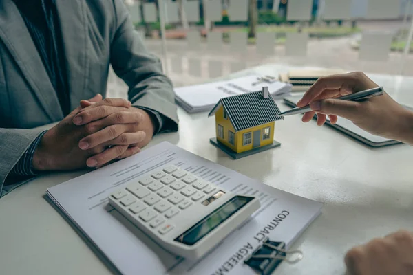 Home agents talk to new home buyers and offer good interest rates and calculate clients on mortgage financing to help make real estate concept decisions.