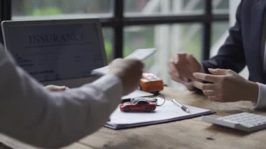 Şık takım elbiseli bir araba satıcısı başarılı iş adamlarına bir araba markası seçimi sunuyor ve araba galerisi sigortası taksitleri için faiz oranları sunuyor..