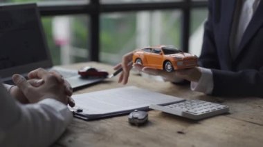 Şık takım elbiseli bir araba satıcısı başarılı iş adamlarına bir araba markası seçimi sunuyor ve araba galerisi sigortası taksitleri için faiz oranları sunuyor..