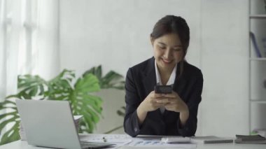 Masa başında dizüstü bilgisayar kullanan bir iş kadını ve iş iletişimi konseptinde konuşan akıllı telefon kadını.