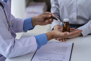 Doktor ve hasta danışma ve teşhisi, hastane tıbbi konseptinin penceresinin yanında yenecek ilaçlarla aynı masada oturmaktadır.