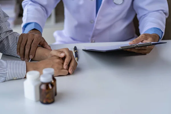 Doctor and patient consulting and diagnosis sitting at a table with advice of medicines to eat near window in hospital medical concept